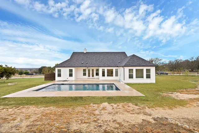 a view of a house with pool and a yard