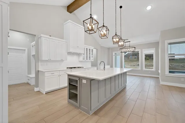 a kitchen with a sink and dishwasher with white cabinets