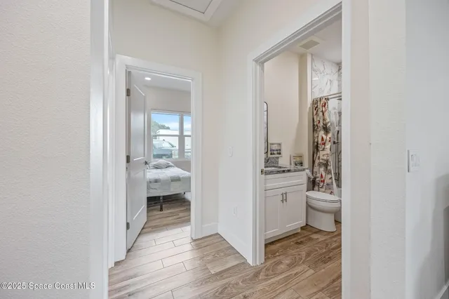 a view of a hallway with bathroom and wooden floor