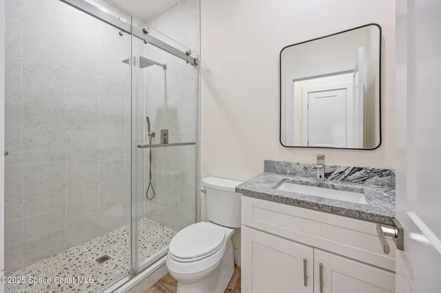 a bathroom with a granite countertop sink toilet mirror and shower