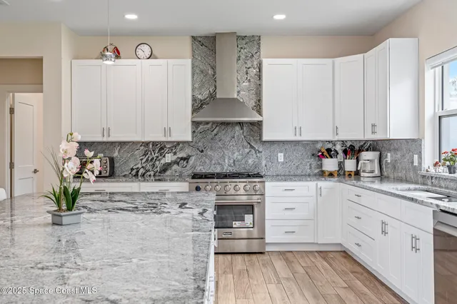 a kitchen with stainless steel appliances granite countertop a stove a sink and white cabinets