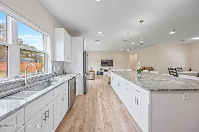 a large kitchen with stainless steel appliances granite countertop a lot of counter space and wooden floors