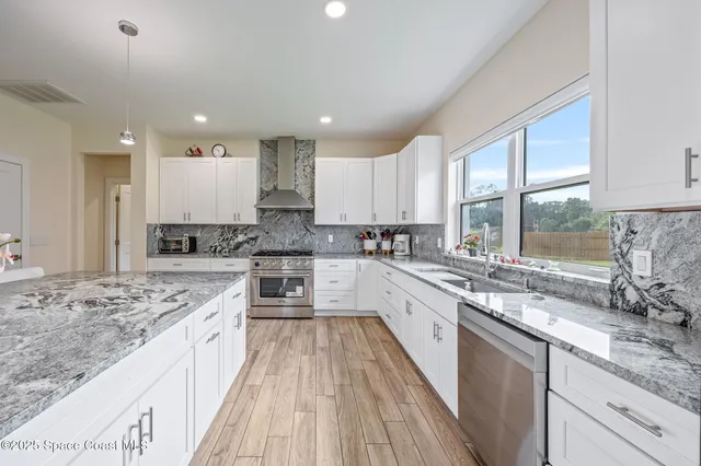 a large kitchen with granite countertop a large window and white cabinets