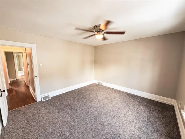 an empty room with a ceiling fan and carpet