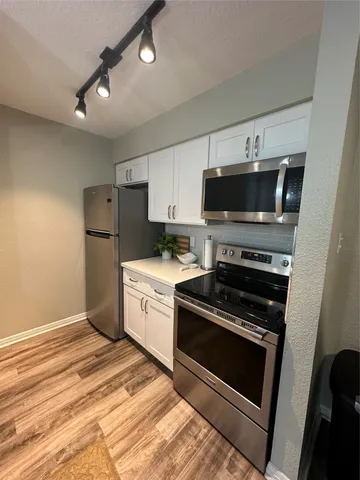 a kitchen with a stove a microwave and white cabinets