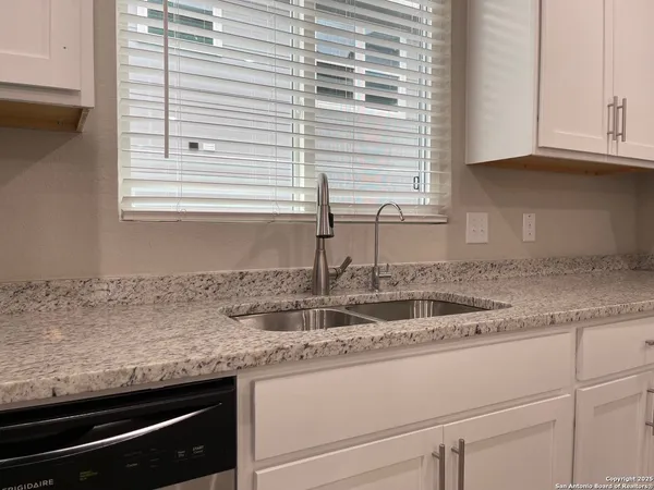 a kitchen with granite countertop white cabinets and a sink