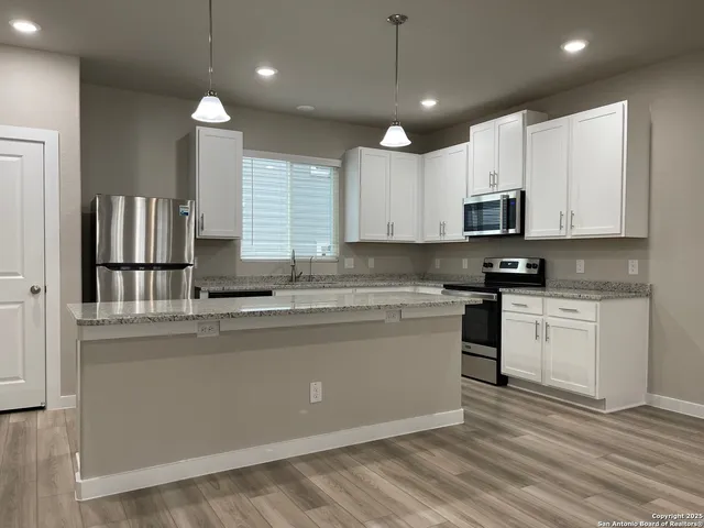 a large kitchen with stainless steel appliances granite countertop a stove a sink and a microwave