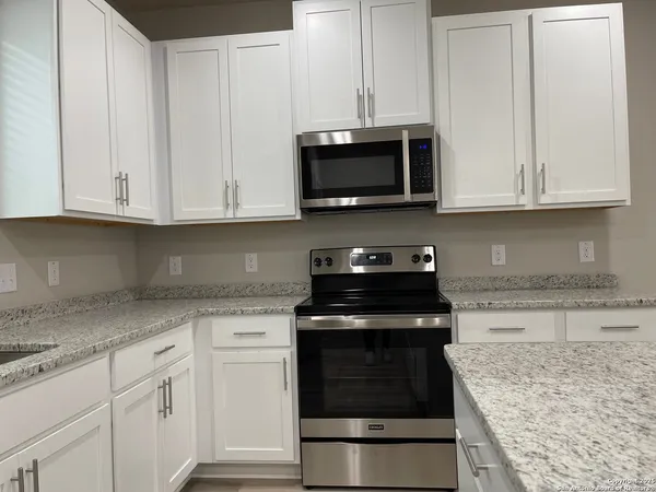 a kitchen with white cabinets and black appliances