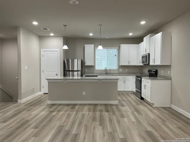 a view of kitchen with granite countertop stainless steel appliances refrigerator sink and cabinets