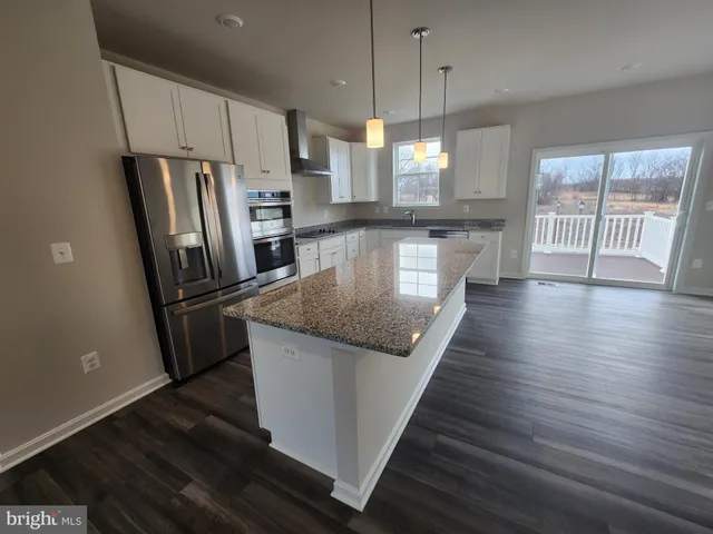 a kitchen with stainless steel appliances granite countertop a refrigerator a stove and a wooden floors