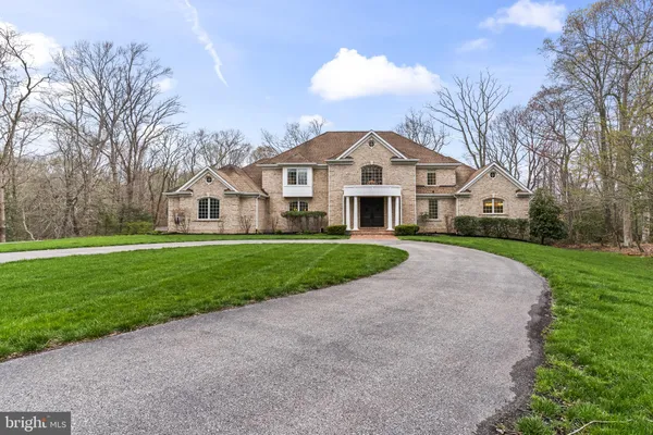 a view of house with a big yard and large trees