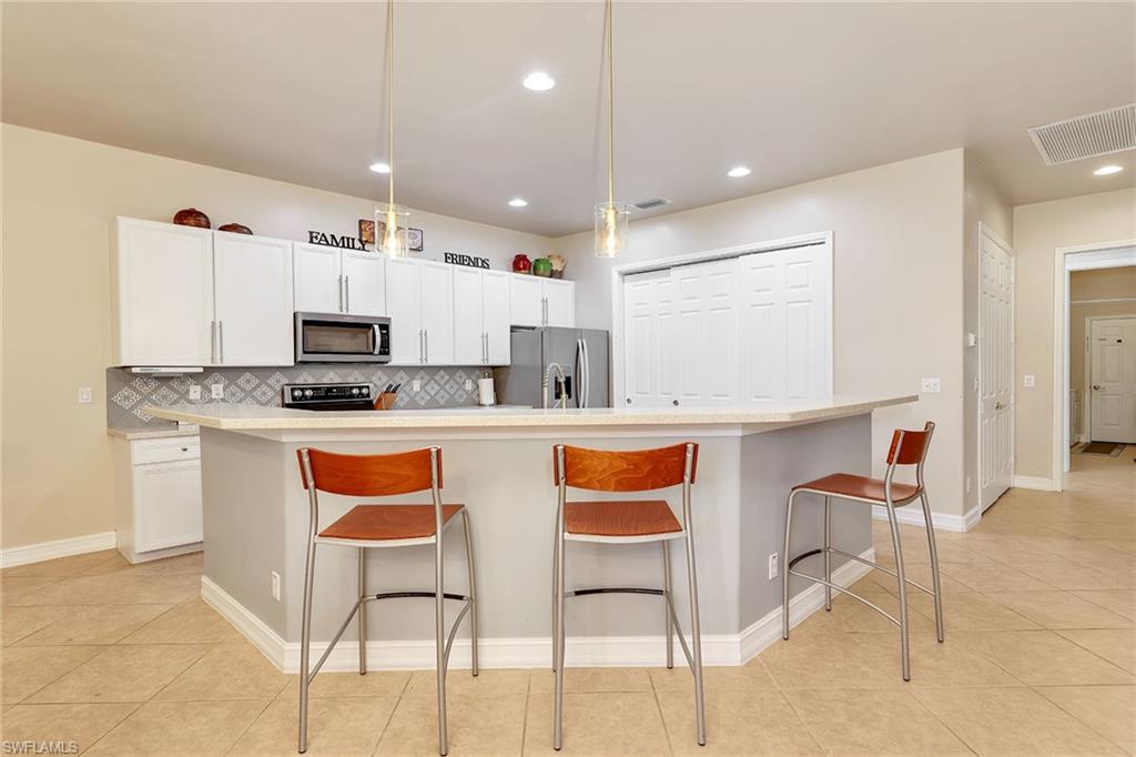 14611 Indigo Lakes Circle Naples, FL 34119 - Photo 12 of 31 a kitchen with stainless steel appliances granite countertop a stove a sink and a refrigerator