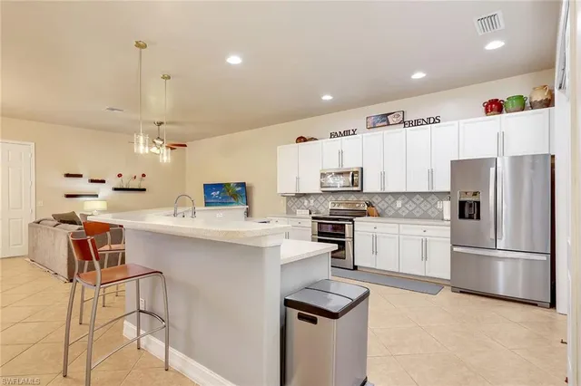 a kitchen with kitchen island white cabinets and stainless steel appliances