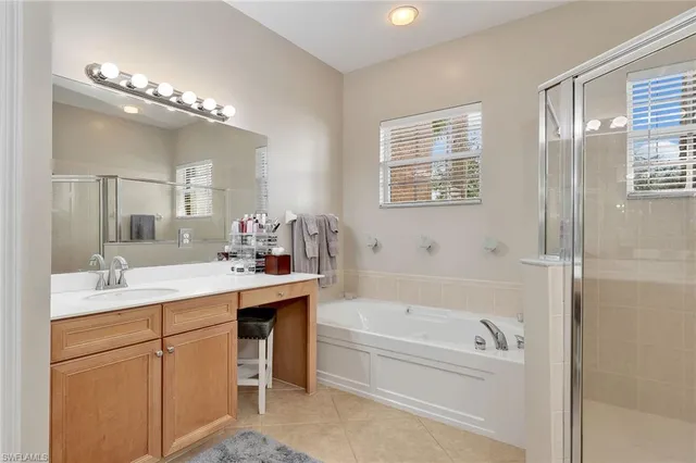 a bathroom with a tub a sink double vanity granite and mirror