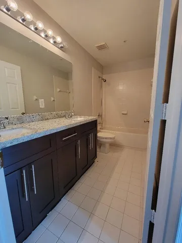 a bathroom with a granite countertop sink a toilet and a mirror