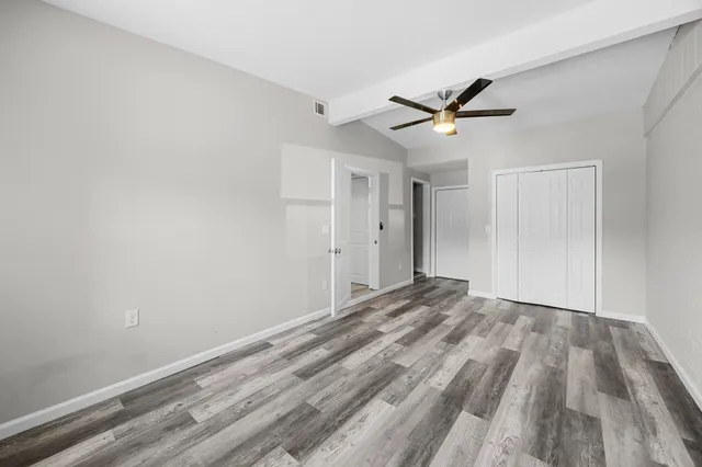 a view of empty room with wooden floor and ceiling fan