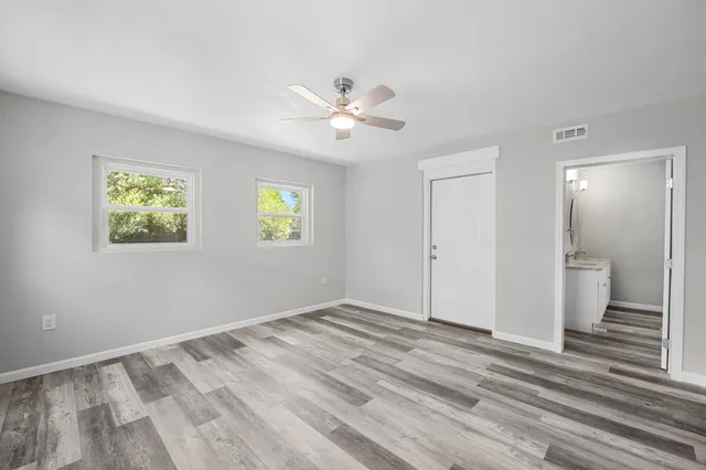 a view of empty room with wooden floor and fan