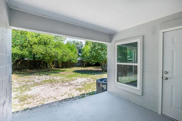 a view of a small yard with wooden fence and large trees