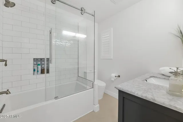 a bathroom with a granite countertop sink a toilet and shower