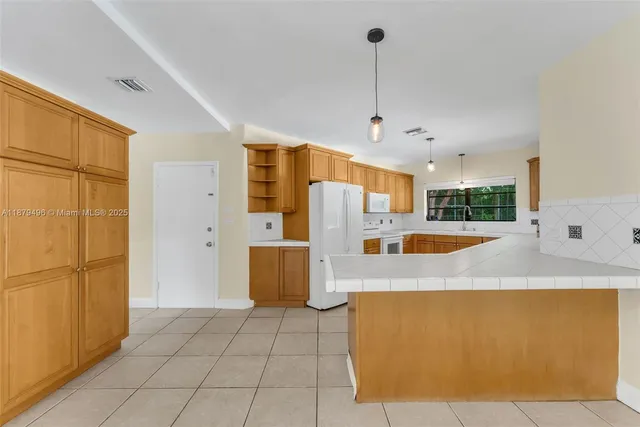 a view of kitchen with stainless steel appliances granite countertop a refrigerator a oven and white cabinets