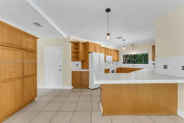 a view of kitchen with stainless steel appliances granite countertop a refrigerator a oven and white cabinets