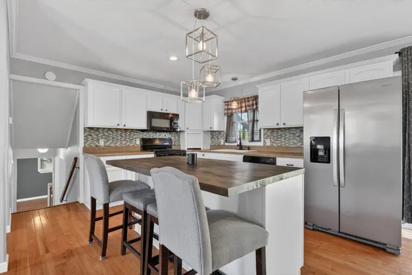 a kitchen with stainless steel appliances granite countertop a dining table chairs refrigerator and sink