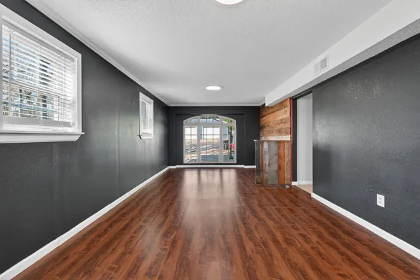 a view of empty room with wooden floor and fan