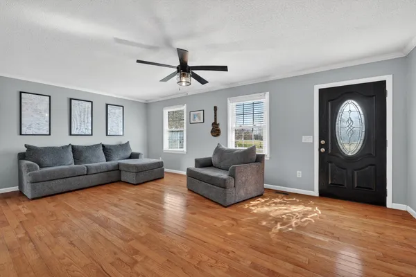 a living room with furniture a large window and a wooden floor