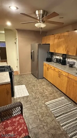 a kitchen with stainless steel appliances kitchen island granite countertop a refrigerator and a stove top oven