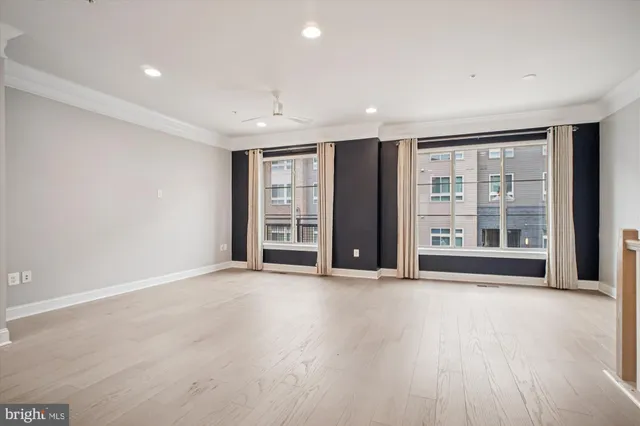a view of an empty room with a window and wooden floor