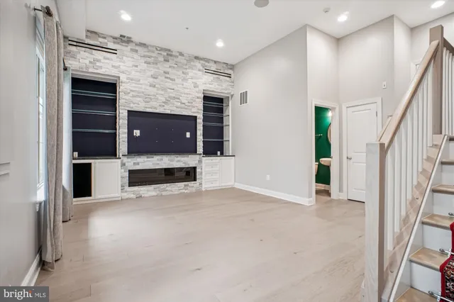 a view of an empty room with a fireplace and a kitchen view