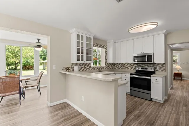 a kitchen with stainless steel appliances granite countertop a stove top oven a sink dishwasher a dining table and chairs with wooden floor