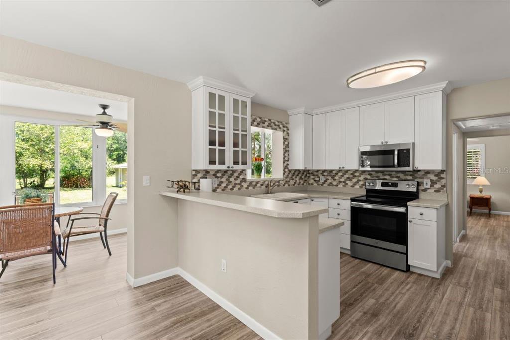 1020 Old Big Tree Road Daytona Beach, FL 32119 - Photo 11 of 37 a kitchen with stainless steel appliances granite countertop a stove top oven a sink dishwasher a dining table and chairs with wooden floor