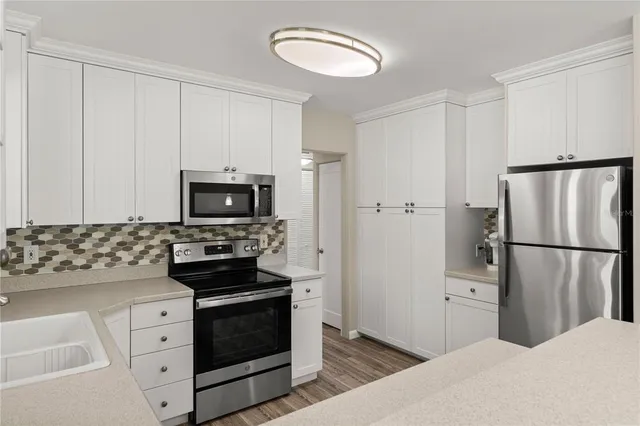 a kitchen with white cabinets and stainless steel appliances