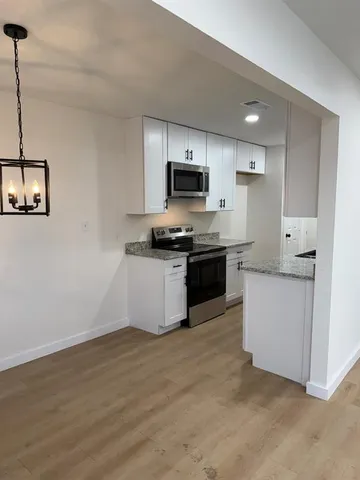 a kitchen with stainless steel appliances granite countertop a stove top oven a sink and a microwave