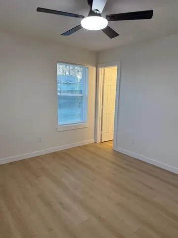 an empty room with windows and fan