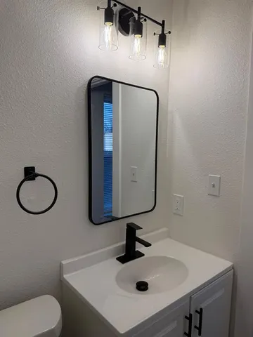 a bathroom with a sink vanity mirror and toilet