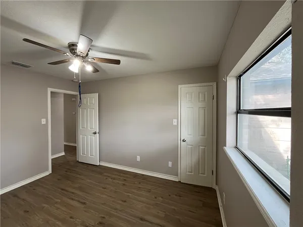 a view of an empty room with window chandelier fan and fire place