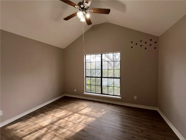 an empty room with wooden floor fan and windows