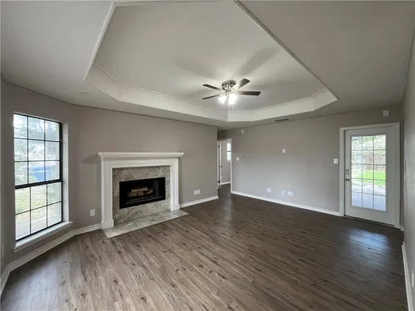 an empty room with wooden floor fireplace and windows
