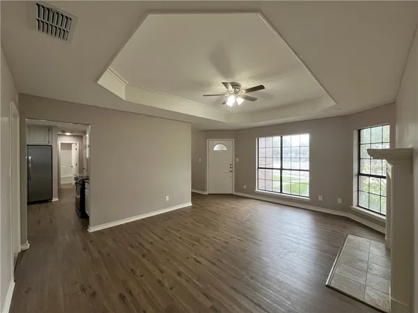 an empty room with wooden floor and windows