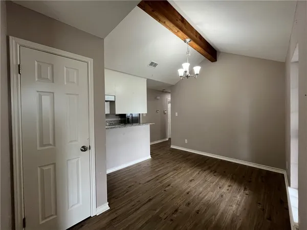 a view of a hallway with wooden floor and a kitchen