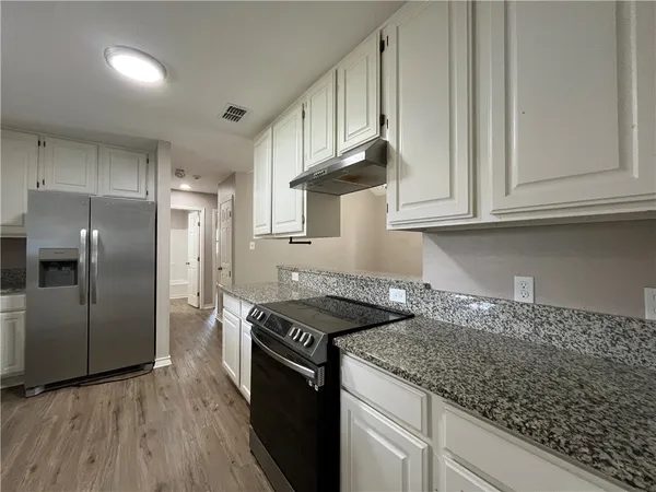 a kitchen with granite countertop a sink a stove and refrigerator