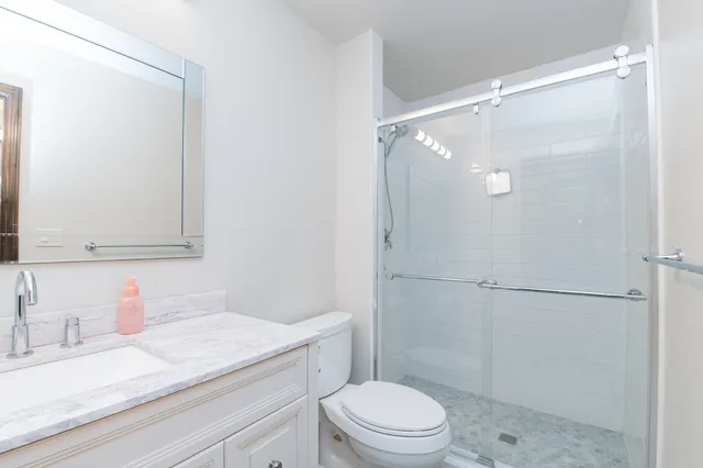 a bathroom with a granite countertop sink mirror vanity and toilet