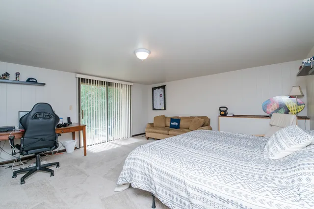 a bedroom with a bed chair and a large window