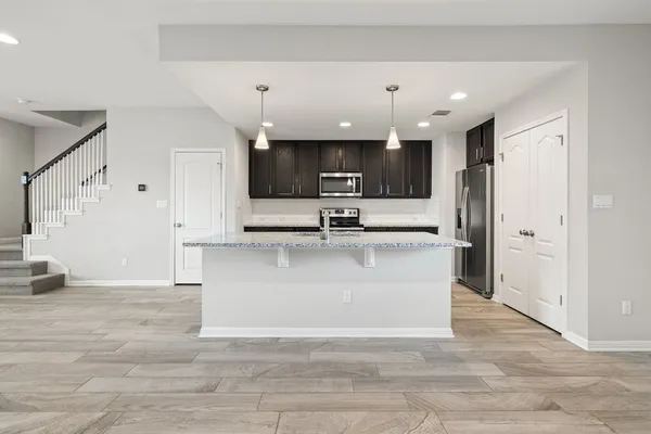 a view of kitchen with stainless steel appliances kitchen island granite countertop a stove a sink a refrigerator and a view of living room
