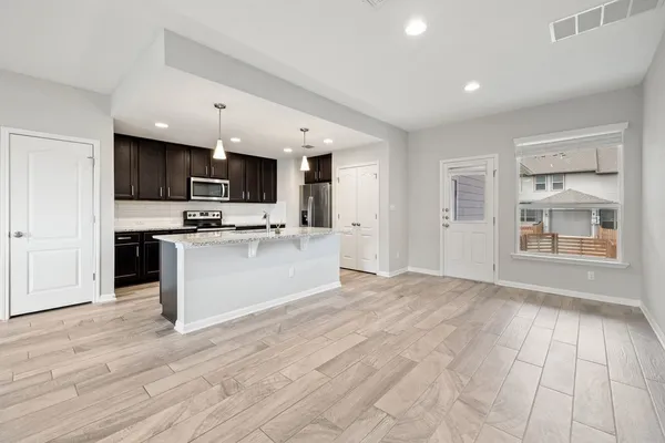 a view of kitchen with stainless steel appliances granite countertop a stove top oven a sink dishwasher a microwave oven and a refrigerator with wooden floor