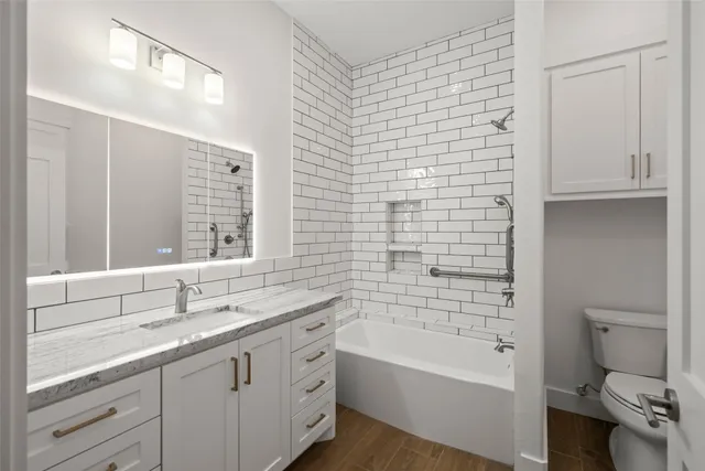 a bathroom with a bathtub sink vanity mirror and toilet