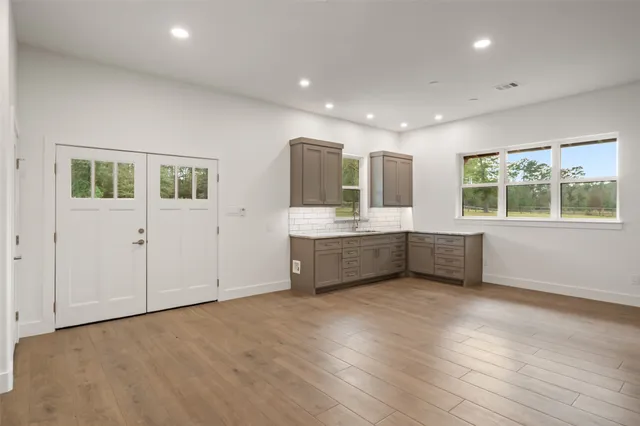 a large white kitchen with a sink wooden cabinet and a granite counter top