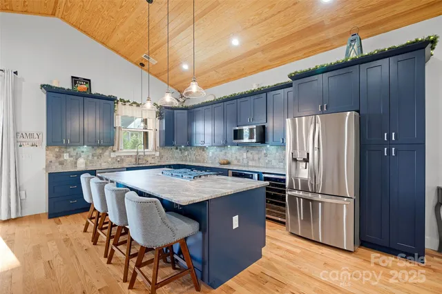 a kitchen with stainless steel appliances granite countertop a table chairs refrigerator and microwave